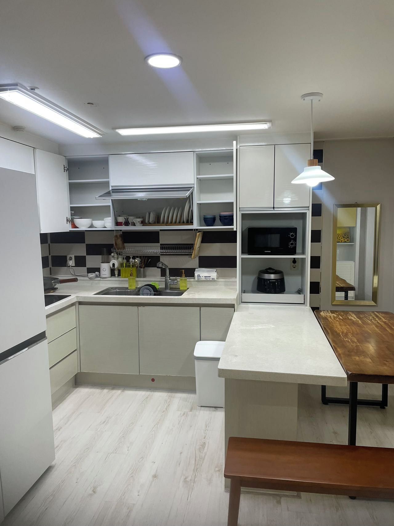 Una cocina moderna con armarios blancos, un microondas integrado y una mesa de comedor de madera.