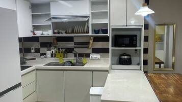 Una cocina moderna con armarios blancos, un microondas integrado y una mesa de comedor de madera.