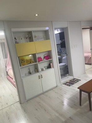 A room with a white wardrobe, a bed with a pink bedspread, and a wooden table. - Lucky Guesthouse (Non-Korean Nationals Women only) (Incheon)
