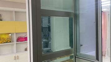 A room with a sliding glass door leading to a bathroom. There is a wooden table and a chair in the room.