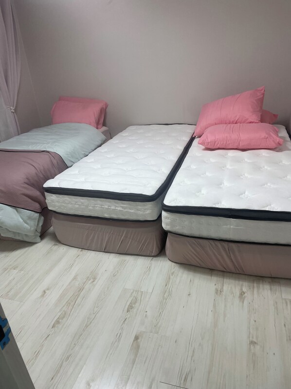 A room with two beds, each with a mattress and pillows.