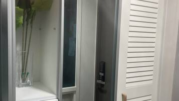 A room with a white door, a glass door, and a shelf with a vase of flowers.