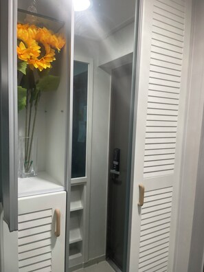 A room with a white door, a glass door, and a shelf with a vase of flowers. - Lucky Guesthouse (Non-Korean Nationals Women only) (Incheon)