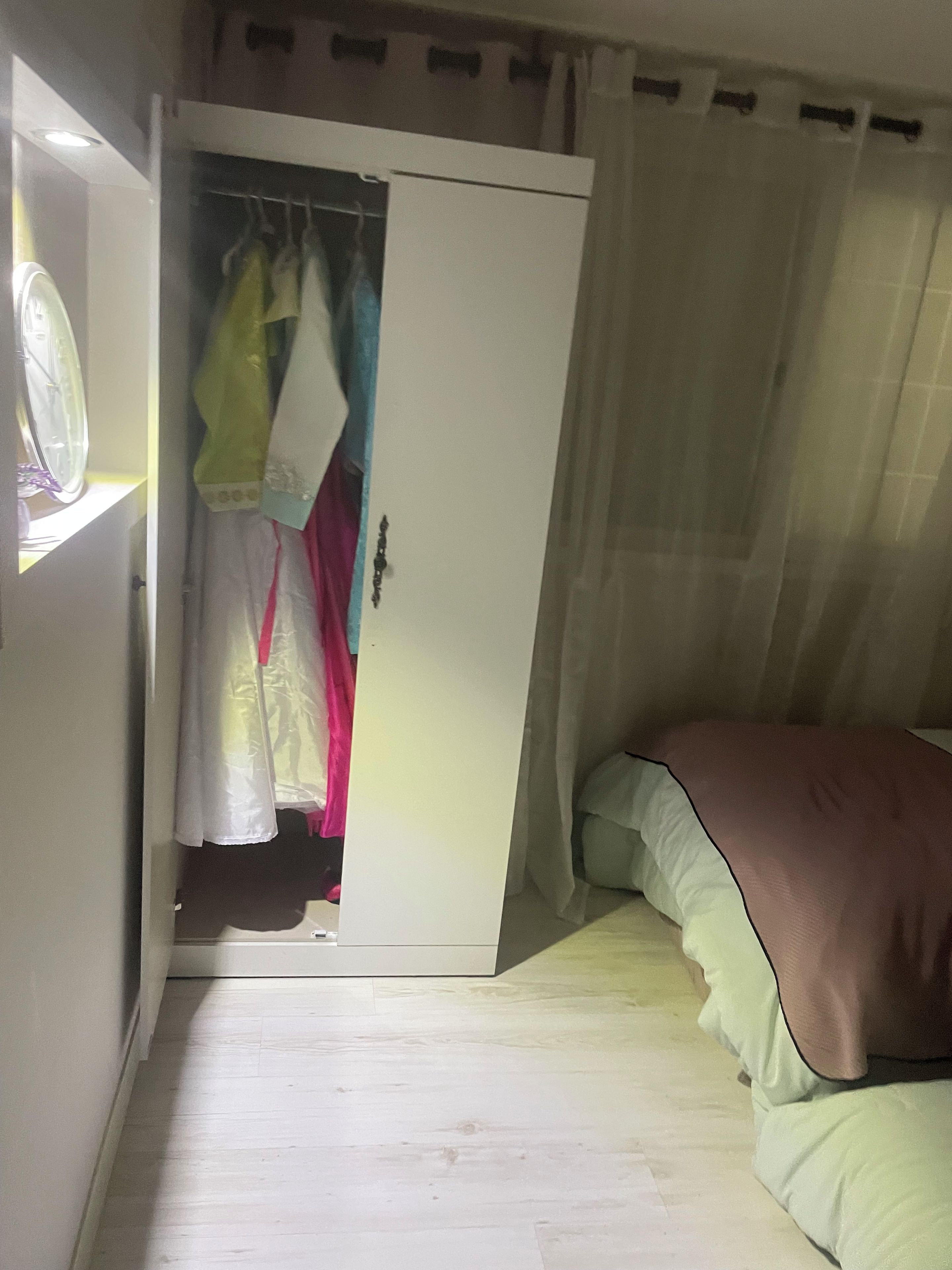 A bedroom with a bed, a wardrobe, and a window with curtains.