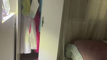 A bedroom with a bed, a wardrobe, and a window with curtains.