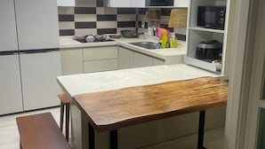 Een moderne keuken met witte kastjes, een houten eettafel en een bank.