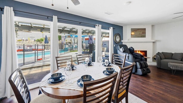 Ein Essbereich mit Tisch für vier Personen, einem Kamin und Blick auf einen Pool.