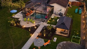 A modern house with a swimming pool, outdoor seating, and a tennis court. - The Tiki Palm- Screened Pool, Mini Golf, Arcade & Creekside Fun (Longwood)