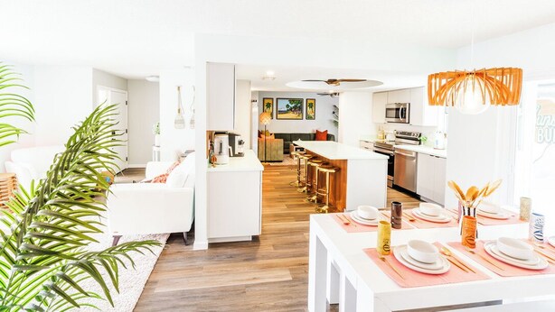 A bright, modern living space with a kitchen, dining area, and a view of the outdoors. - The Tiki Palm- Screened Pool, Mini Golf, Arcade & Creekside Fun (Longwood)