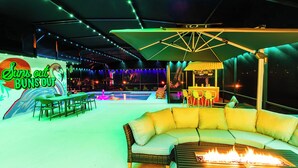 An outdoor seating area with a pool, a tiki bar, and a neon sign. - The Tiki Palm- Screened Pool, Mini Golf, Arcade & Creekside Fun (Longwood)