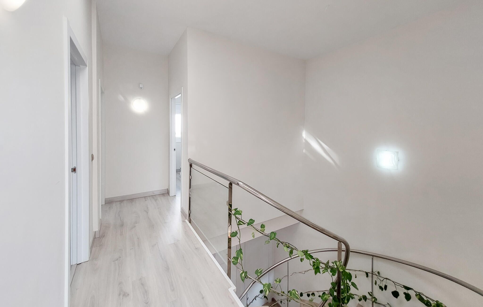 Un interior moderno con una escalera, paredes blancas y piso de madera.