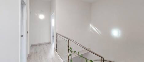 Un interior moderno con una escalera, paredes blancas y piso de madera.
