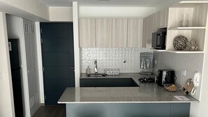 Una cocina moderna con una isla central, armarios oscuros y un salpicadero claro.