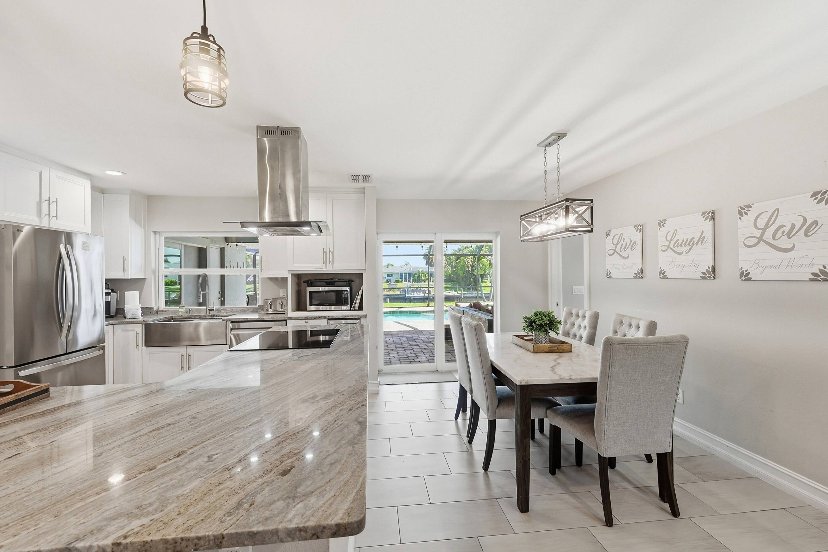 Una cocina moderna con una isla grande, electrodomésticos de acero inoxidable y un comedor con mesa y sillas.