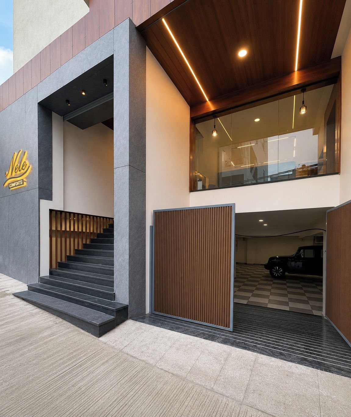 A modern building with a staircase leading to a second-floor balcony, a car parked inside, and a logo on the facade.