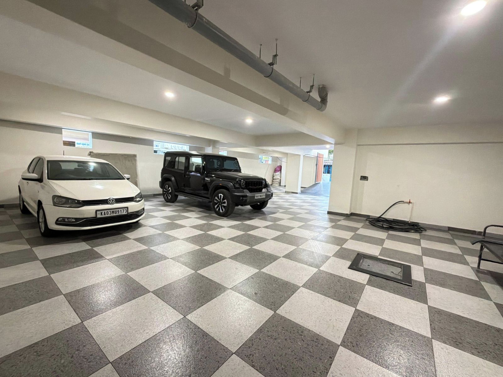 Un parcheggio multipiano con due auto parcheggiate, un pavimento a scacchi e un'uscita ben visibile.