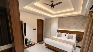 A modern hotel room with a large bed, a ceiling fan, a TV, and a minibar. - Nele comforts (Bengaluru,)