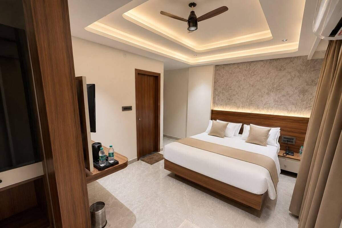 Quarto de hotel moderno com uma cama grande, ventoinha no teto, televisão e minibar.