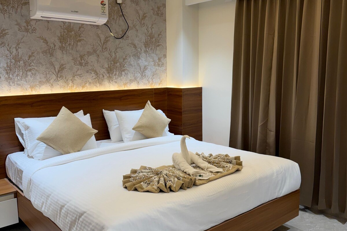 A modern hotel room with a large bed, a ceiling fan, an air conditioning unit, and a window with curtains.