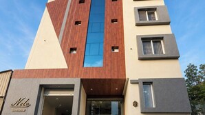A multi-story hotel with a modern design, featuring a prominent vertical wooden panel, a glass facade, and a sign reading 'Nele COMFORTS'. - Nele comforts (Bengaluru,)