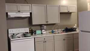 A kitchen with white cabinets, a stove, a blender, and a refrigerator. - Comfortable and unique 5-bedroom apartment with AC in Fort Valley (Fort Valley)