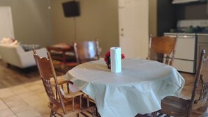 A dining area with a round table, chairs, a white tablecloth, and a candle. - Comfortable and unique 5-bedroom apartment with AC in Fort Valley (Fort Valley)
