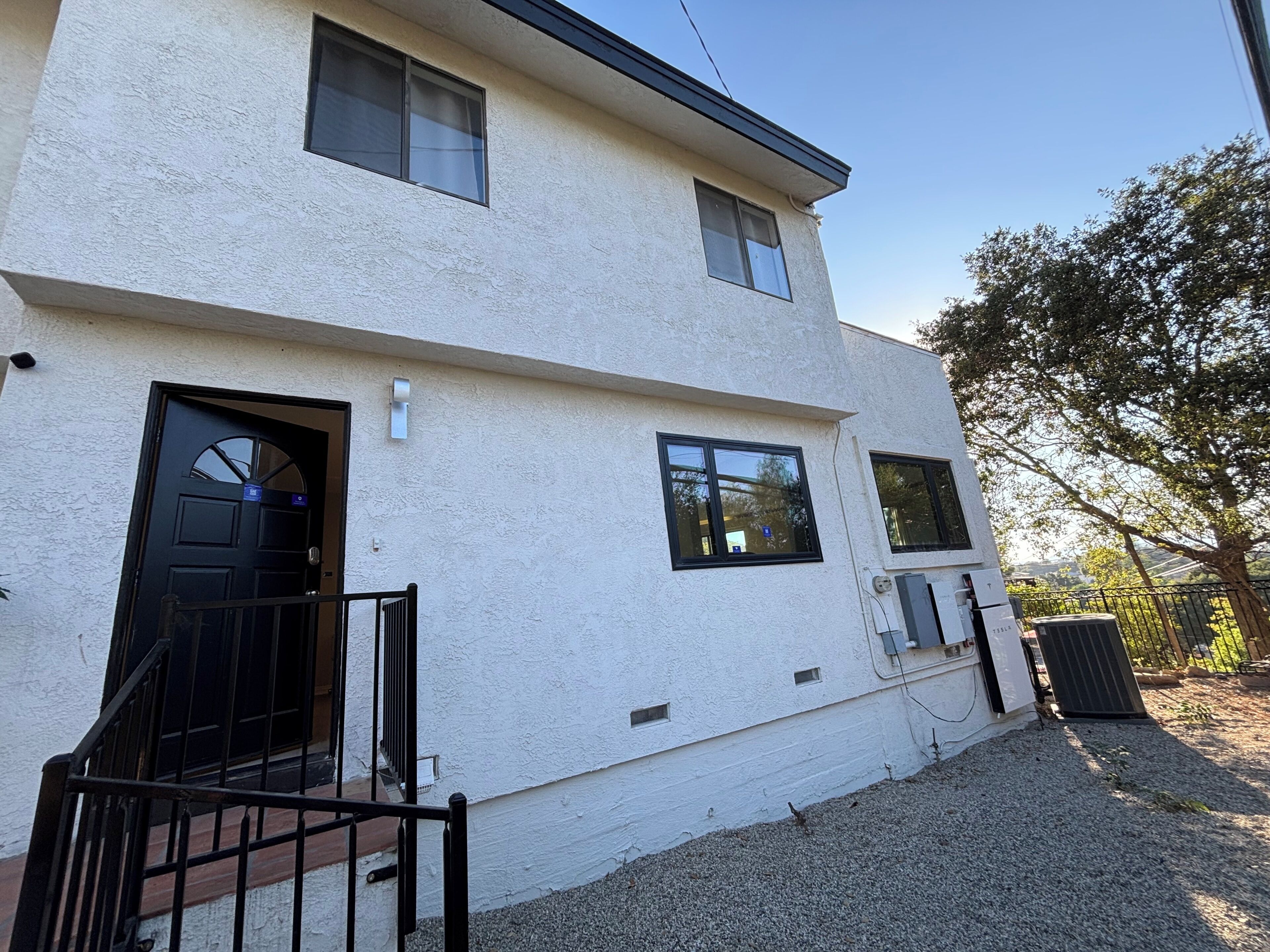 A two-story building with a white exterior, a black door, and a small front porch.