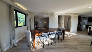 Een eethoek met een houten tafel en stoelen, een televisie en een trap naar een hoger niveau.