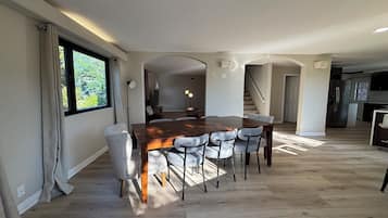 Een eethoek met een houten tafel en stoelen, een televisie en een trap naar een hoger niveau.