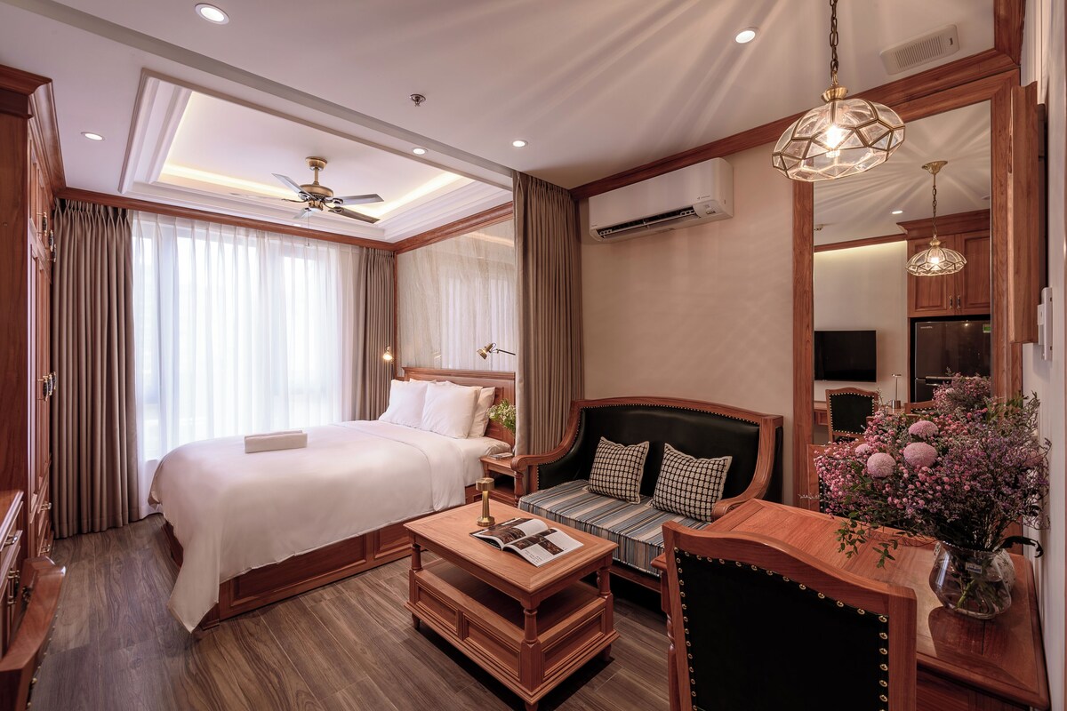 Een hotelkamer met een bed, bank, houten salontafel en een spiegel.