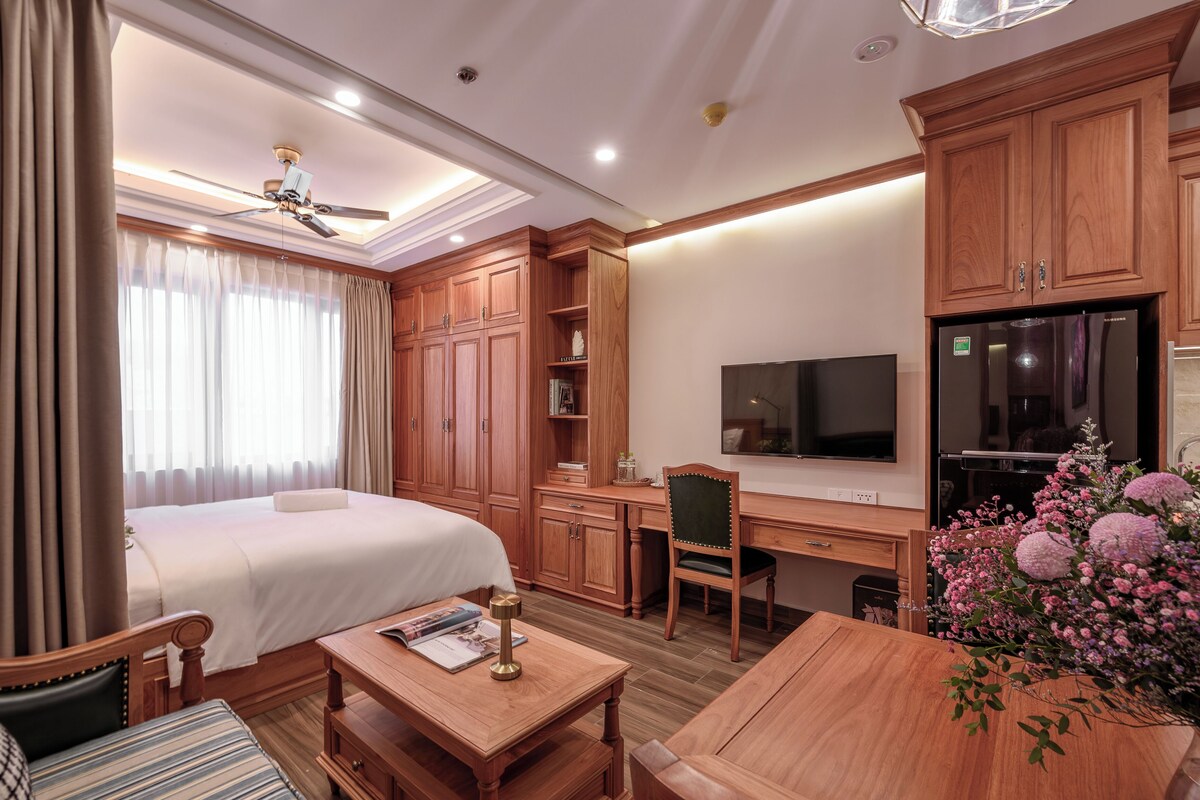 Een hotelkamer met een bed, bureau, stoel, televisie en een eettafel.