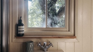 A bathroom with a window, a sink, and a bottle.