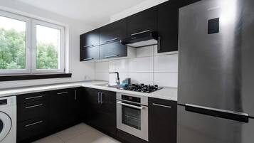 Una cocina moderna con electrodomésticos de acero inoxidable, armarios negros y un ventanal que proporciona luz natural.
