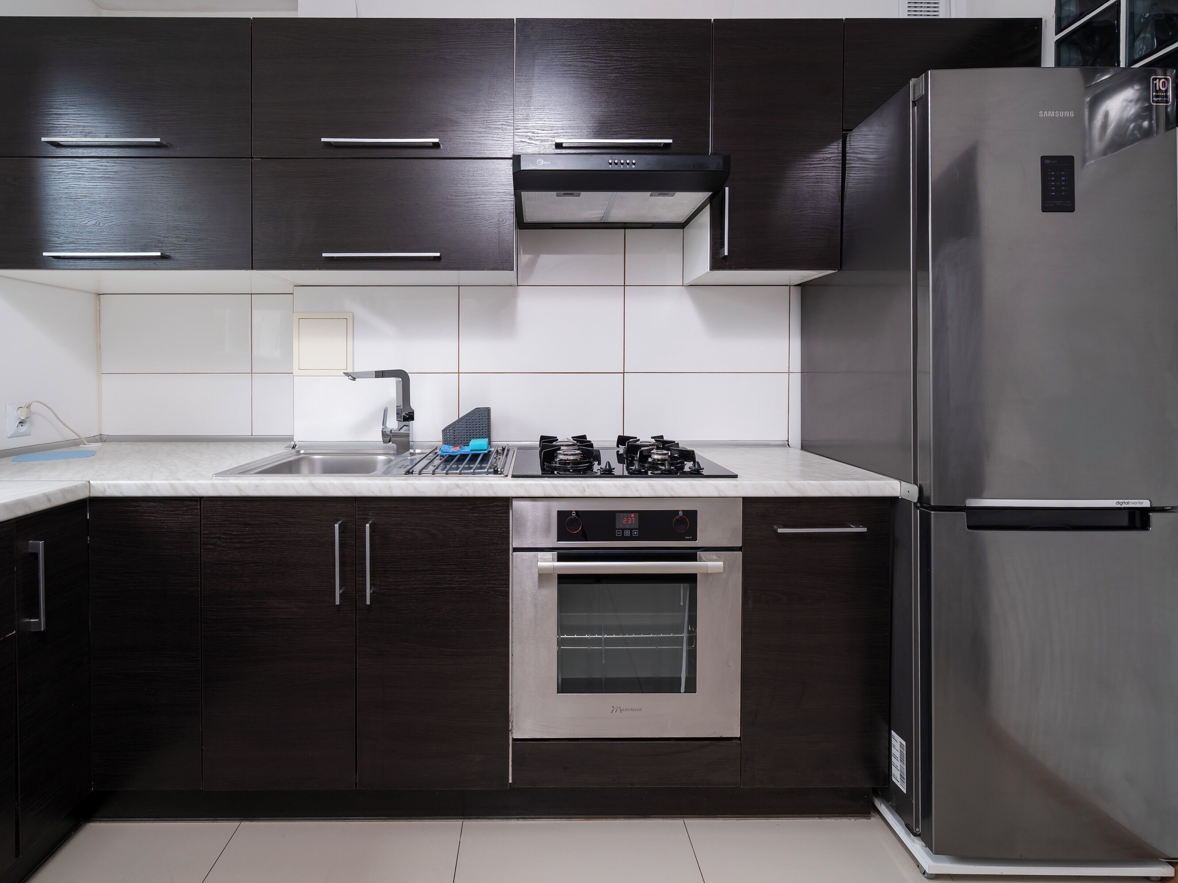 Una cocina moderna con armarios de madera oscura, un refrigerador de acero inoxidable, un horno empotrado y una estufa a gas.