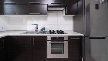 Una cocina moderna con armarios de madera oscura, un refrigerador de acero inoxidable, un horno empotrado y una estufa a gas.