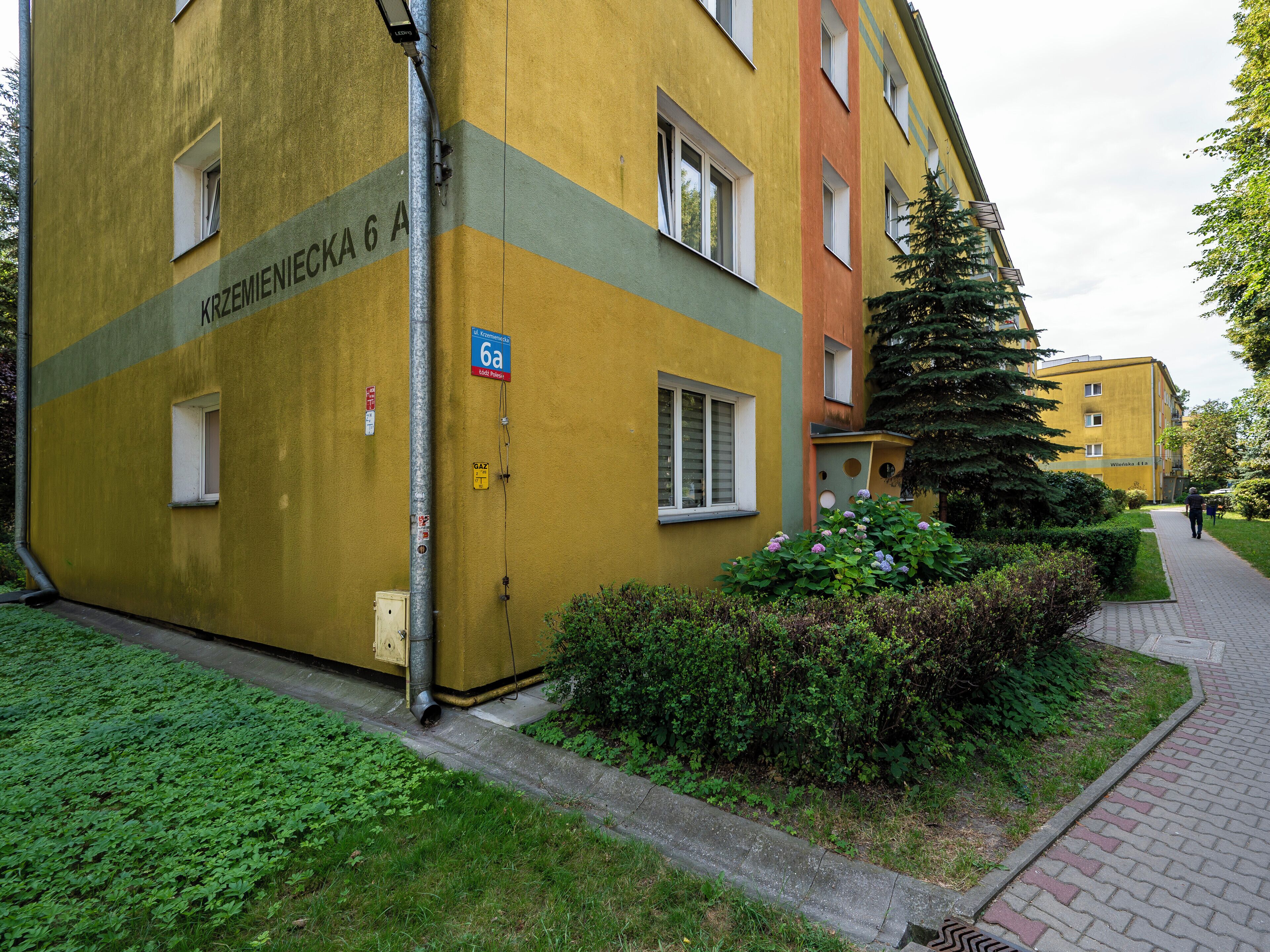 A yellow building with a sign reading 'Krzemieniecka 6a' and a '6a' parking sign.