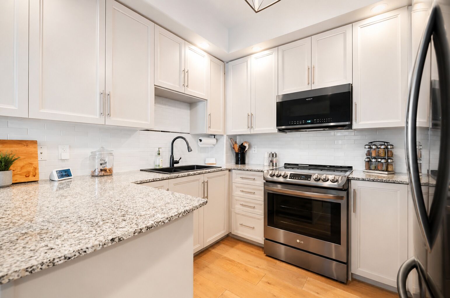 A modern kitchen with white cabinets, a granite countertop, a stainless steel stove, and a built-in microwave.