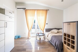 Ein Schlafzimmer mit Bett, Nachttisch, Kleiderschrank und einem Fenster mit Vorhängen.