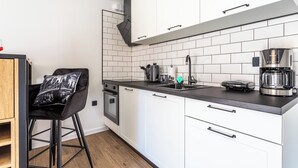 Eine moderne Küche mit weißen Schränken, einer schwarzen Arbeitsplatte und einer Kaffeemaschine.