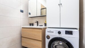 Ein modernes Badezimmer mit Waschmaschine, Holzschränken und Fliesenboden.