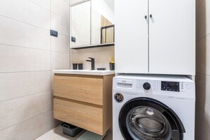 Ein modernes Badezimmer mit Waschmaschine, Holzschränken und Fliesenboden.