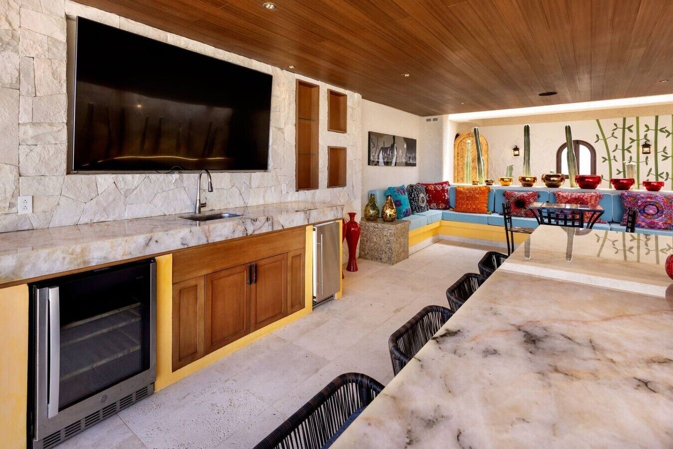 A modern kitchen with a built-in TV, wooden cabinets, and a stone backsplash.