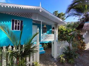 Een turquoise huis met een witte veranda en een witte hekwerk.