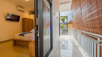 A hotel corridor with a bed, a television displaying 'NETFLIX', and a view of the outside balcony.