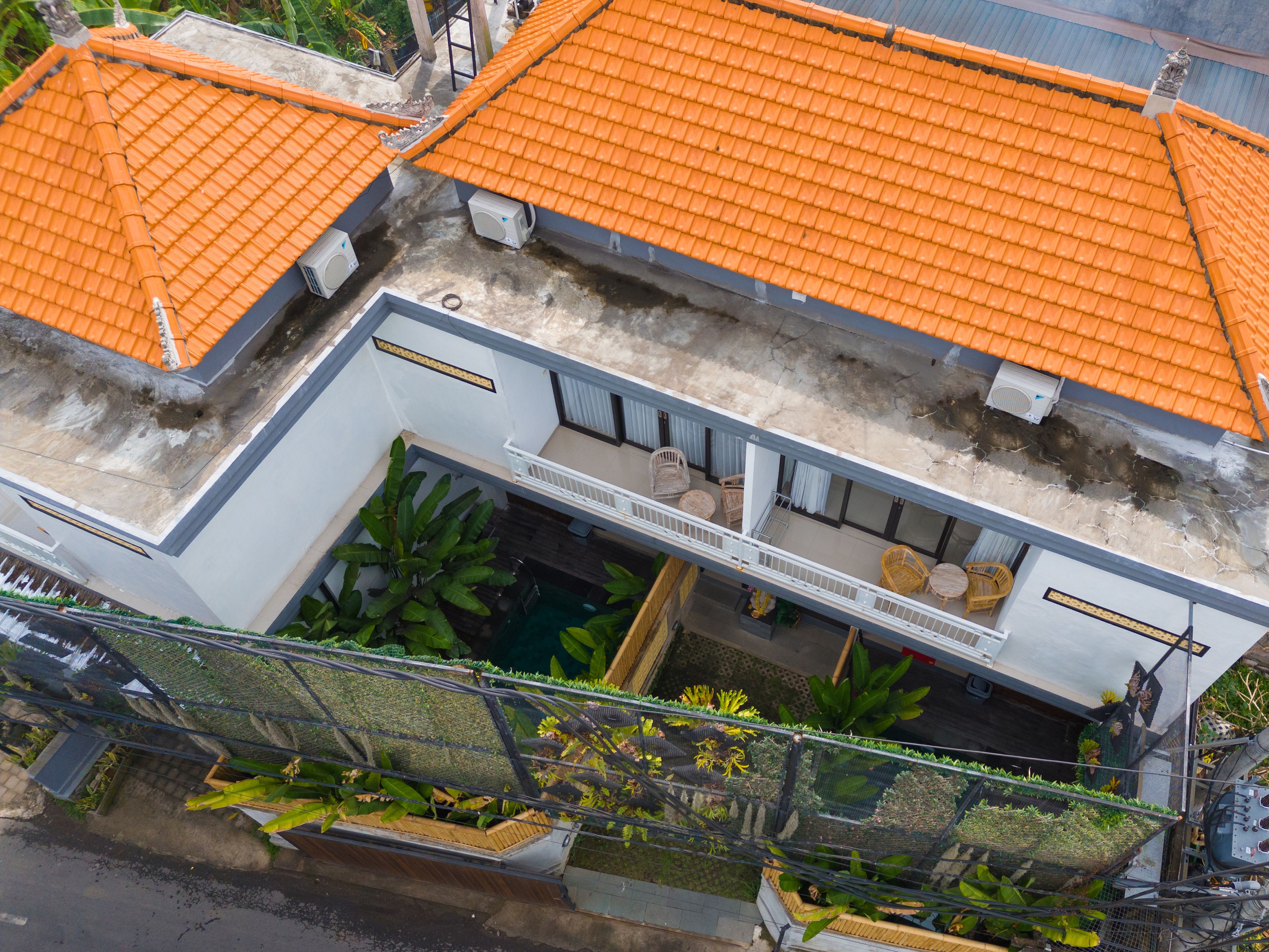 Un edificio de varios pisos con tejados de tejas anaranjadas, un espacio de estar al aire libre cubierto y una piscina pequeña.