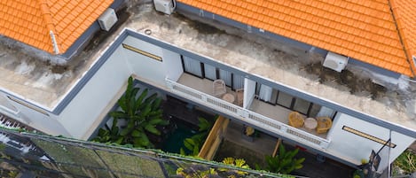 Un edificio de varios pisos con tejados de tejas anaranjadas, un espacio de estar al aire libre cubierto y una piscina pequeña.