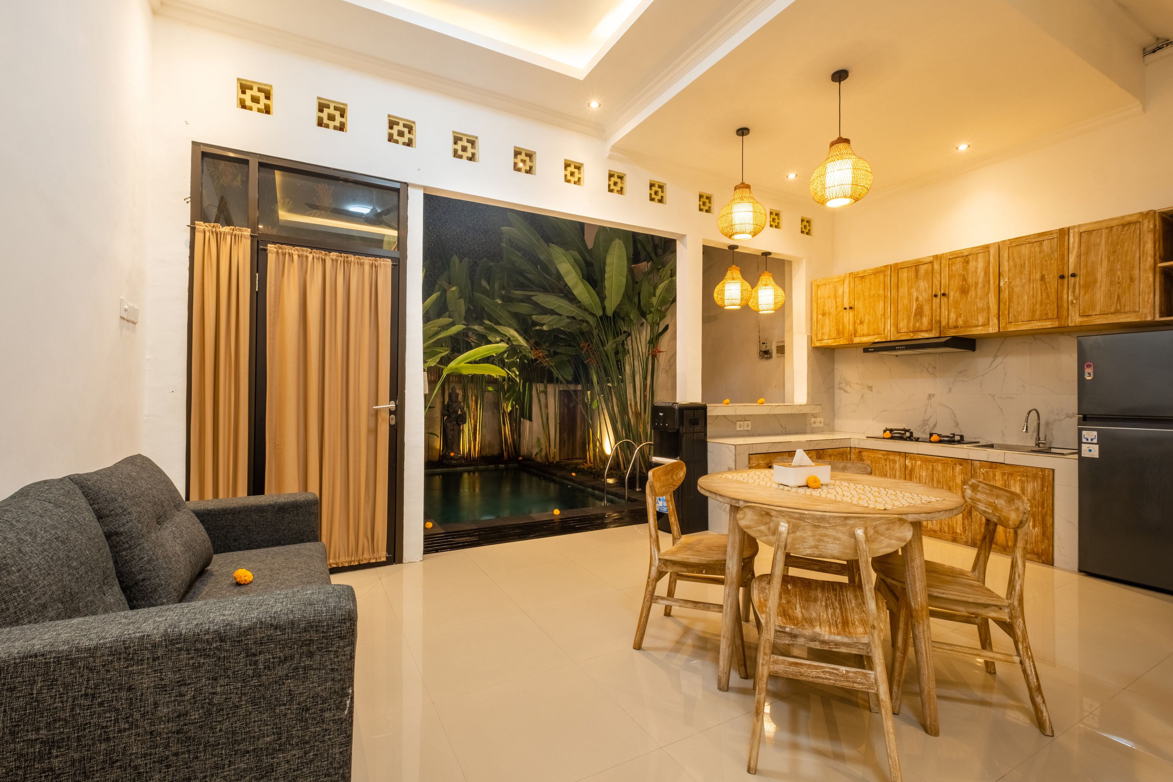 Una cocina moderna con armarios de madera, una mesa de comedor con sillas y un ventanal corredero que da a una zona de piscina.