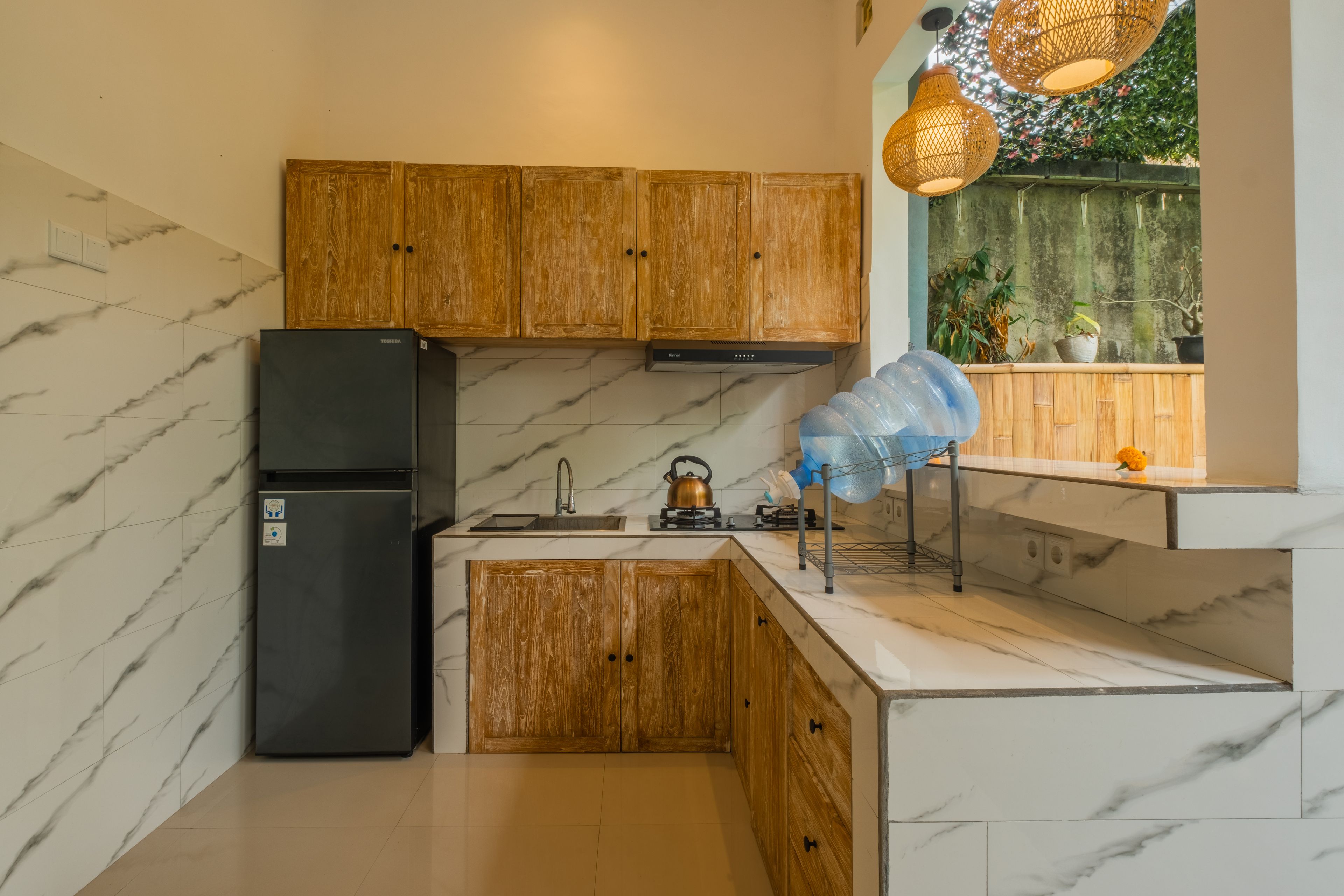 A compact kitchen with wooden cabinets, a black refrigerator, a sink, and a stove.
