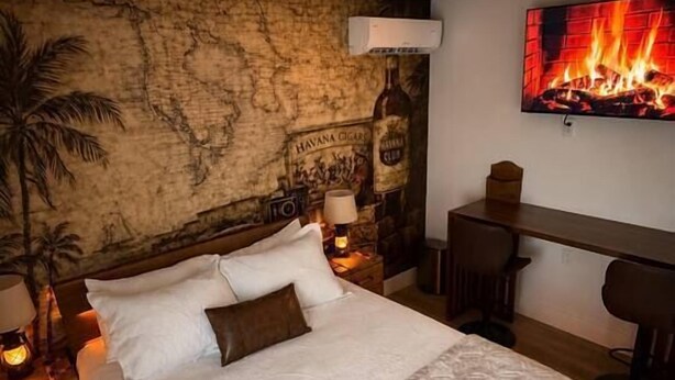 Ein Schlafzimmer mit einem großen Bett, einer Wand voller Karten, einem Fernseher mit Kamin-Simulation und einem Schreibtisch mit Stühlen.