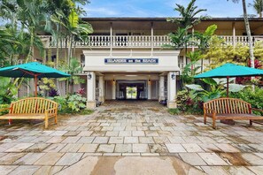 A hotel entrance with a sign reading 'Islander on the Beach,' stone-paved walkway, wooden benches, and tropical plants. - *NEW* Ocean-View Kapaa Studio Near the Beach and Pool (Kapaa)